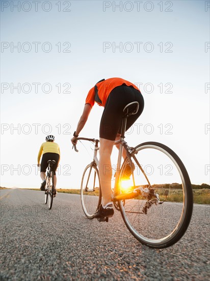 Mid adult couple cycling on empty road.