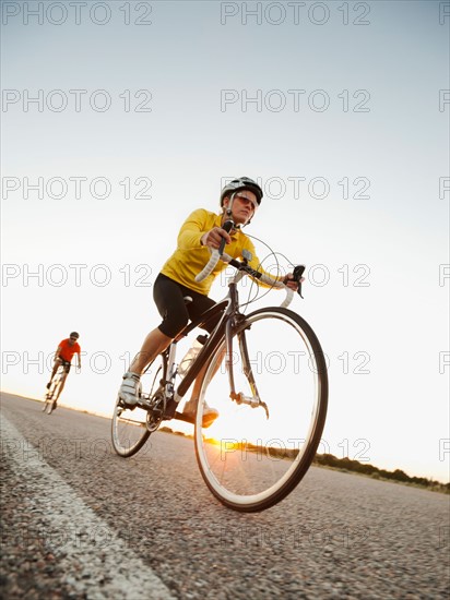 Mid adult couple cycling on empty road. Photo: Erik Isakson