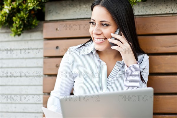 Portrait of young businesswoman sitting on bench using laptop. Photo: Take A Pix Media