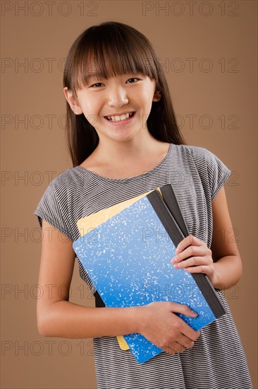 Studio portrait of girl (10-11) holding book. Photo : Rob Lewine