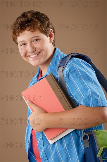 Studio portrait of boy (12-13) with backpack and books. Photo : Rob Lewine