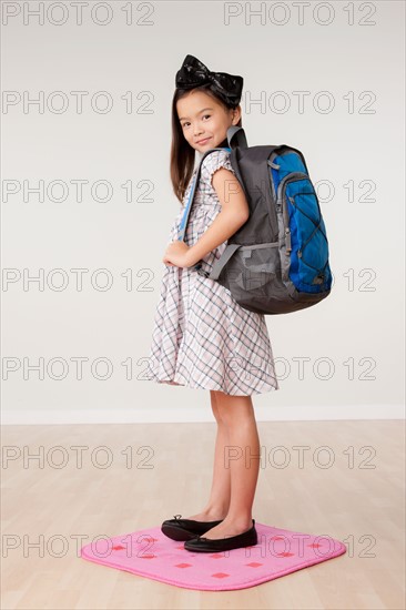 Studio portrait of girl (8-9) carrying backpack. Photo: Rob Lewine