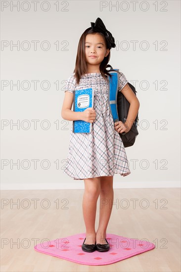 Studio portrait of girl (8-9) carrying backpack. Photo : Rob Lewine