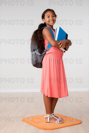 Studio portrait of girl (8-9) carrying backpack. Photo : Rob Lewine