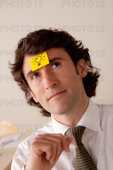 Studio portrait of businessman with adhesive note on forehead. Photo : Rob Lewine