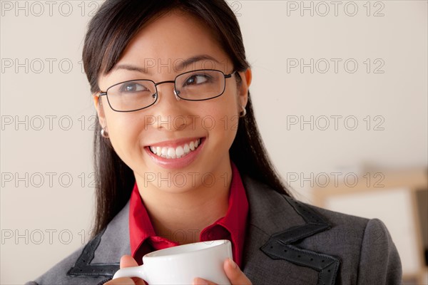 Studio portrait of businesswoman holding cup. Photo : Rob Lewine