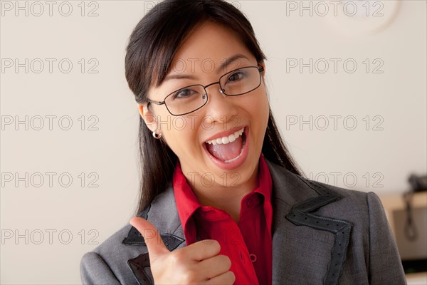 Studio portrait of businesswoman showing thumbs-up. Photo : Rob Lewine