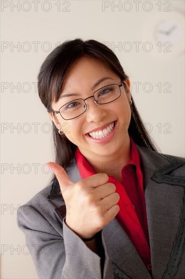 Studio portrait of businesswoman showing thumbs-up. Photo: Rob Lewine