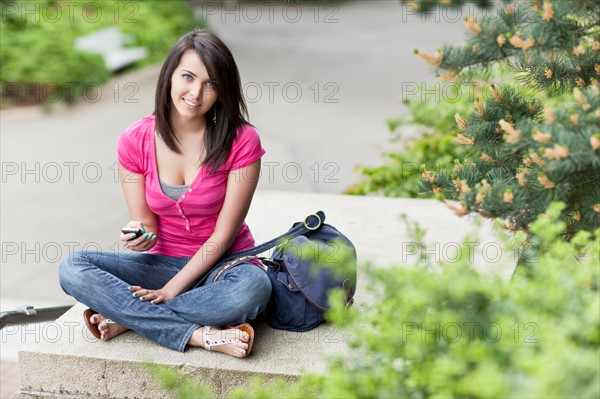 Portrait of woman text-messaging in park. Photo: Take A Pix Media