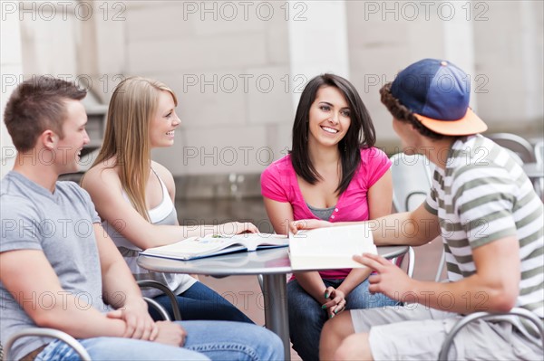 Four college students sitting at cafe table. Photo: Take A Pix Media