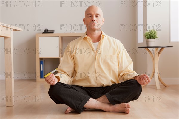 Mature businessman meditating in office. Photo: Rob Lewine