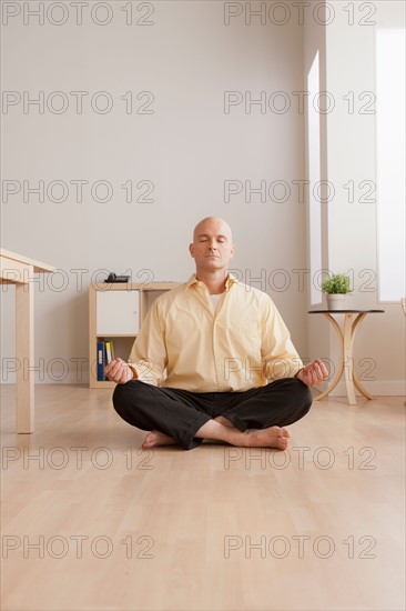 Mature businessman meditating in office. Photo : Rob Lewine