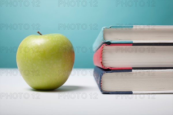 Studio shot of green apple and textbooks. Photo : Winslow Productions