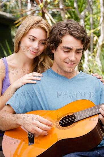 Young couple in park, man playing guitar. Photo : Rob Lewine