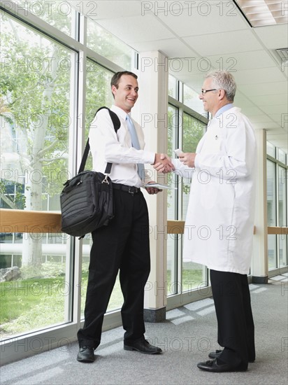 Doctor talking with pharmaceutical representative in hospital corridor. Photo: Erik Isakson