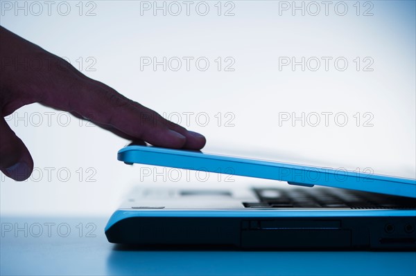 Studio shot of hand closing laptop.