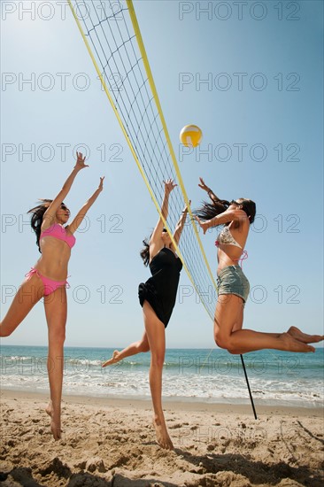 Three attractive young women playing beach volleyball . Photo: Erik Isakson