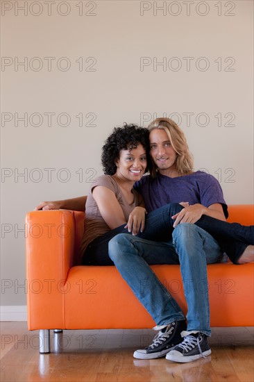 Portrait of young couple sitting on sofa. Photo: Rob Lewine