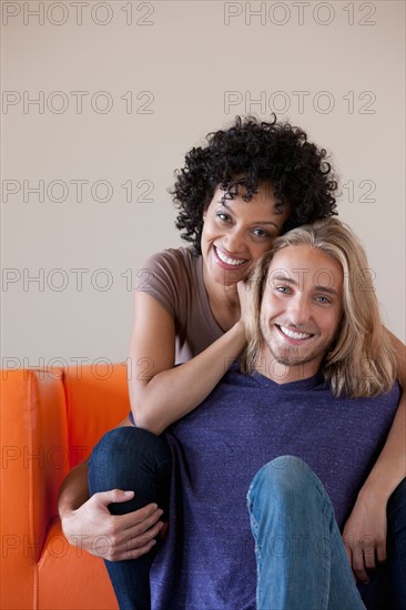 Portrait of young couple sitting on sofa. Photo : Rob Lewine