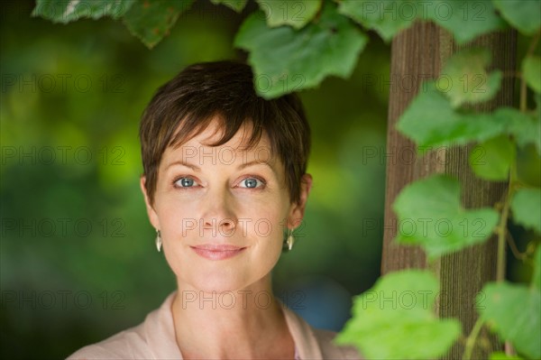 Portrait of mature woman standing next to ivy.