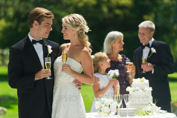 Bride and groom at wedding reception, people in background.