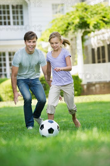 Father and daughter (10-11) playing soccer.