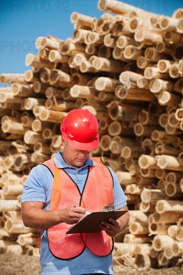 Engineer in front of stack of timber.