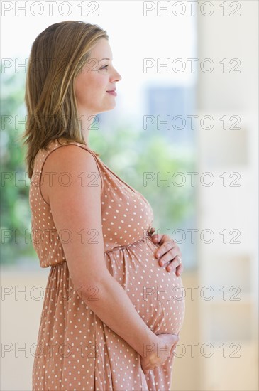 Pregnant woman looking through window.