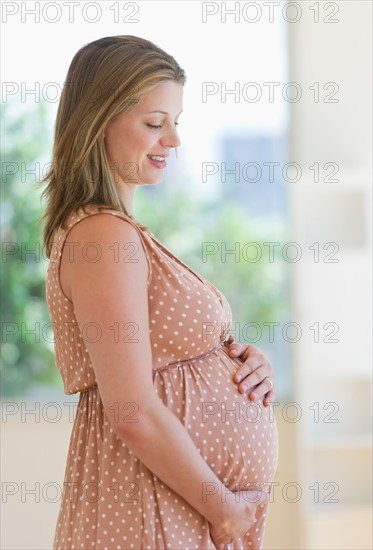 Pregnant woman looking through window.