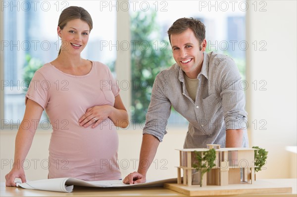 Young couple with blueprints and house model.