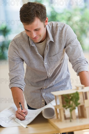 Young man doing notes at blueprints.