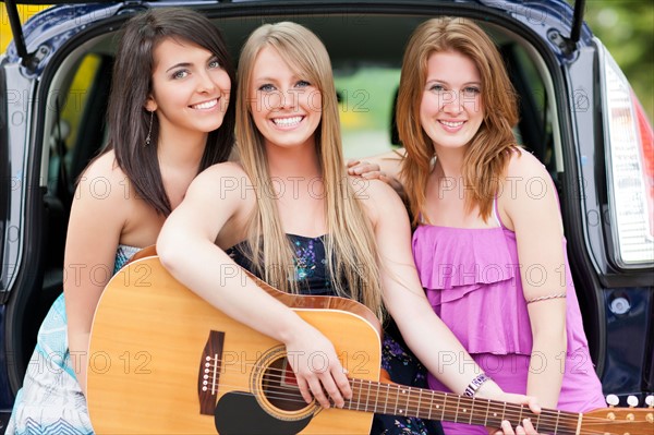 Portrait of young women with guitar by car. Photo: Take A Pix Media