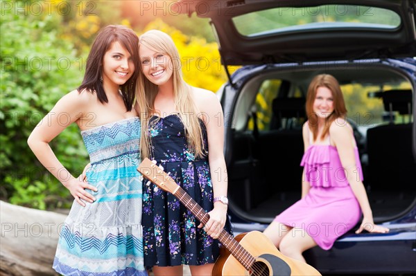 Portrait of young women with guitar by car. Photo : Take A Pix Media