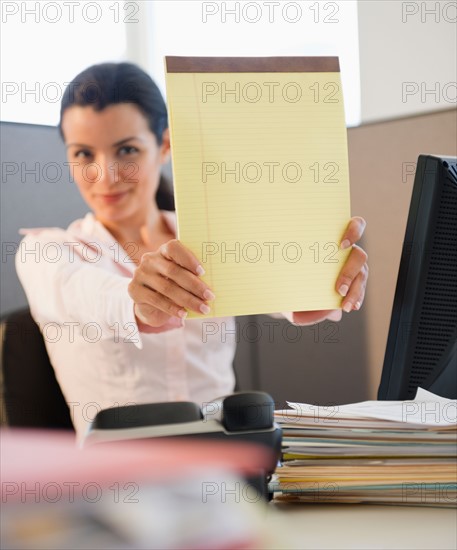 Businesswoman showing blank notepad. Photo : Jamie Grill