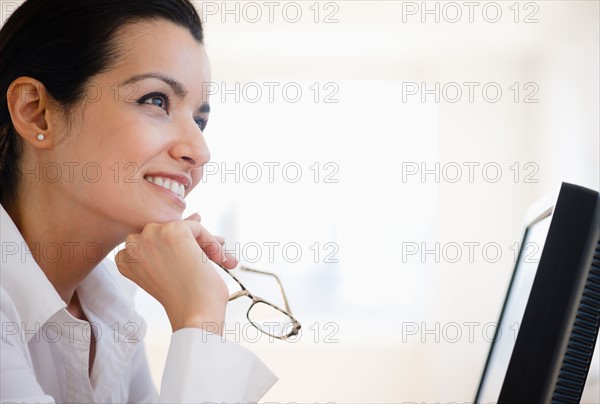 Businesswoman daydreaming at desk in office. Photo : Jamie Grill