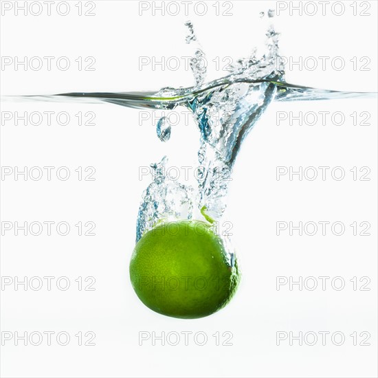 Studio shot of green apple falling into water.