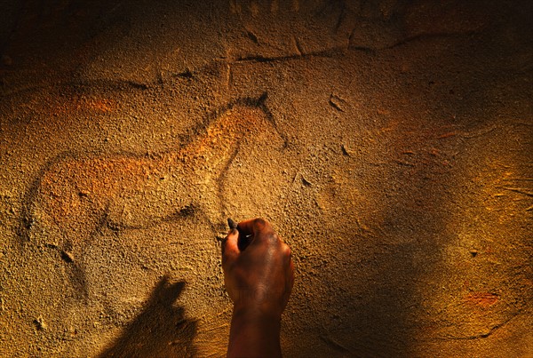 Studio shot of hand making cave painting of horse.