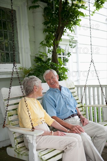 Senior couple sitting on porch swing.