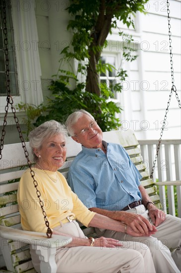 Senior couple sitting on porch swing.