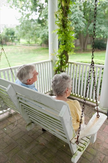 Senior couple sitting on porch swing.