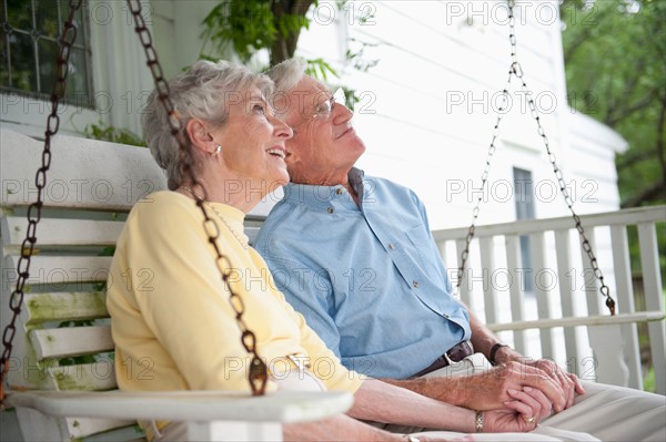 Senior couple sitting on porch swing.