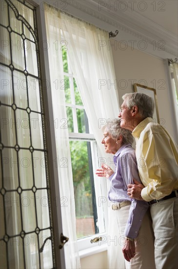 Senior couple looking through window.