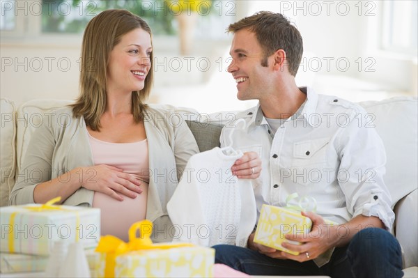 Young couple opening gifts for baby.