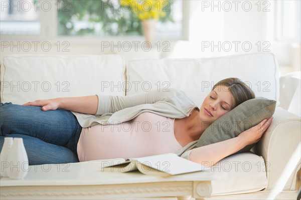 Young pregnant woman sleeping on sofa.