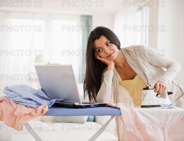 Woman ironing and using laptop. Photo: Jamie Grill