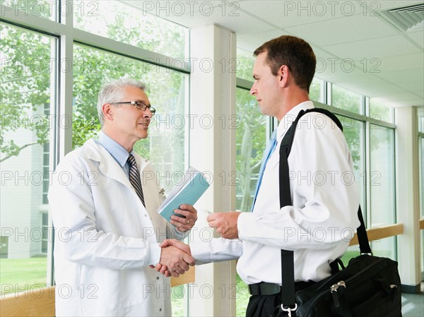 Doctor talking with pharmaceutical representative in hospital corridor.