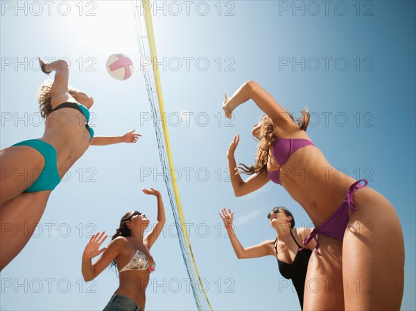 Group of young women playing beach volleyball .