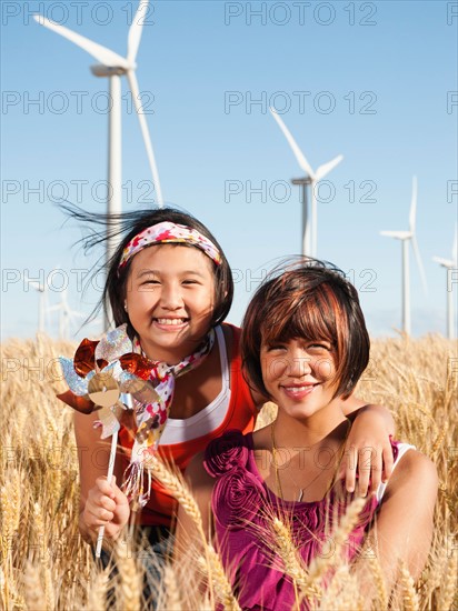 USA, Oregon, Wasco, Portrait of two girls (10-11, 12-13) standing in wheat field, wind turbines in background.
