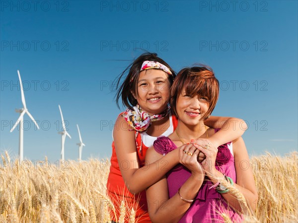 USA, Oregon, Wasco, Girl (10-11) and mother standing in wheat field in front of wind turbines. Photo: Erik Isakson