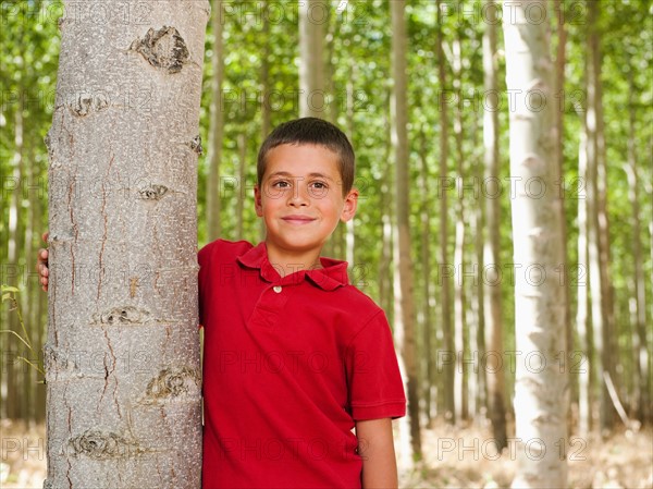 USA, Oregon, Boardman, Boy (8-9) standing between poplar trees in tree farm.